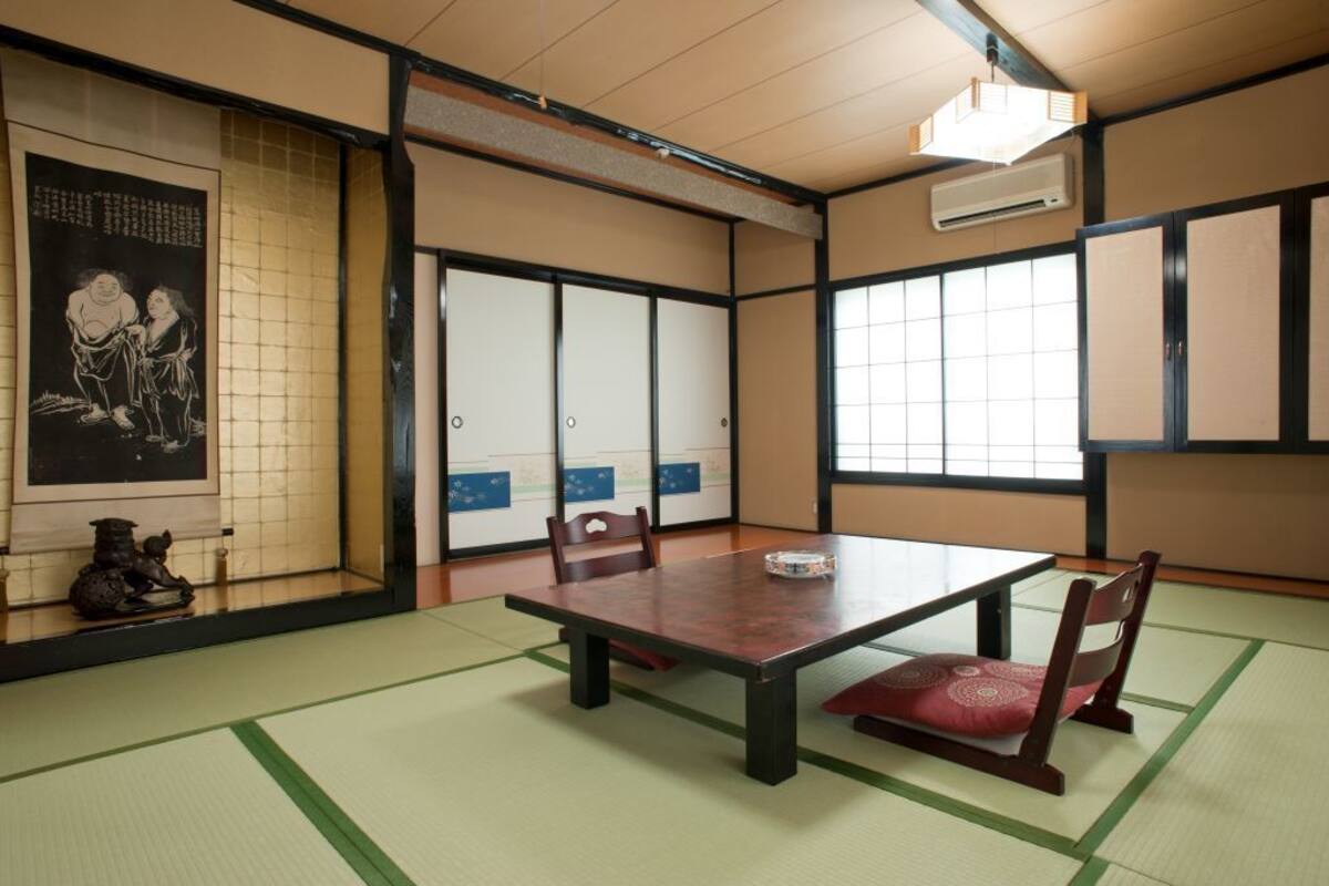 Una habitación japonesa tradicional con suelo de tatami, una mesa baja y puertas correderas.