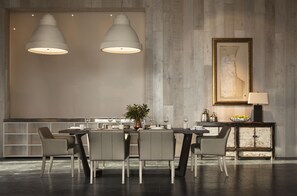 A modern dining area with a large table, multiple chairs, pendant lighting, and a decorative painting on the wall. - Kinloch Manor & Villas (Kinloch)