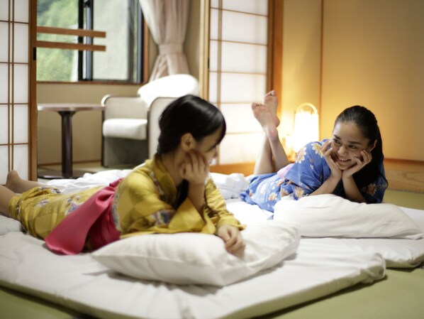 A room with a bed, a window with curtains, and a bedside table.