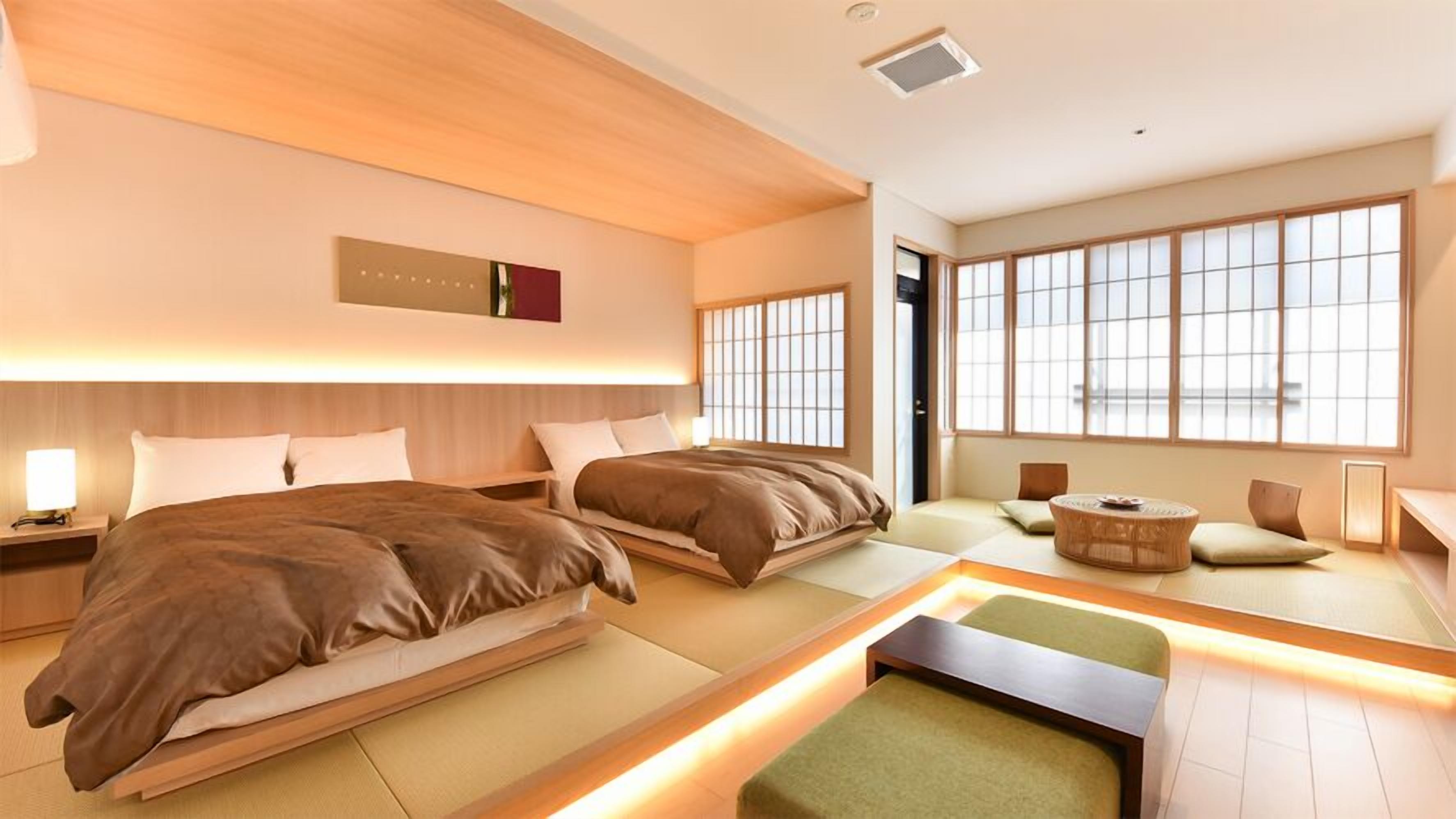 Una habitación de hotel moderna con dos camas, una zona de estar y ventanas amplias.