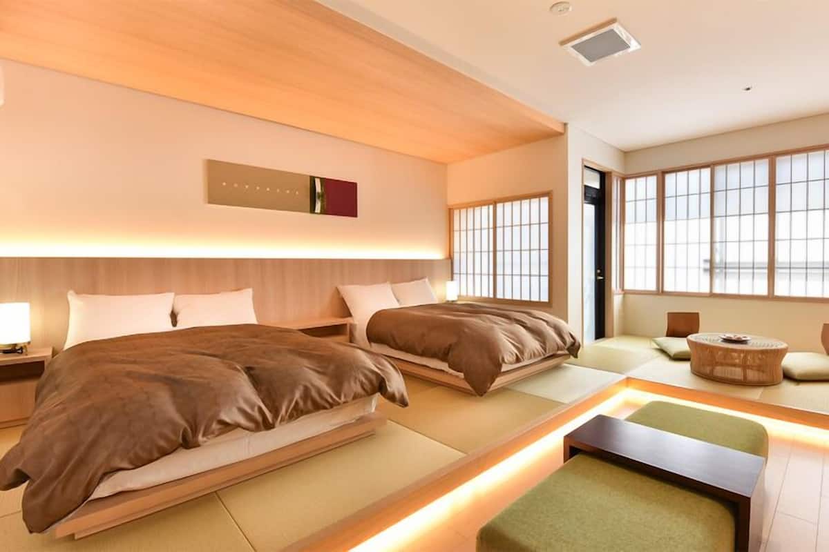 Et moderne hotelværelse med to senge, et siddeområde og store vinduer.