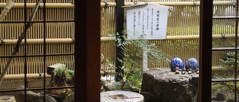 A traditional Japanese room with tatami flooring, a shoji screen, and a small garden area with rocks and a stone lantern.