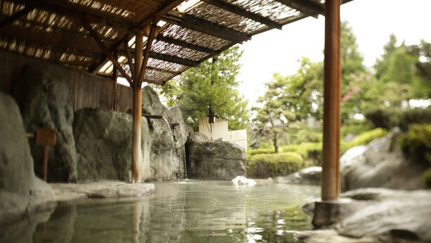 A traditional Japanese onsen with a wooden structure, a rock formation, and a clear water pool. - Yuruino Yado Keizan (Achi)