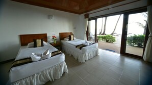 A hotel room with two beds, a wooden ceiling, and a large sliding glass door leading to a balcony with a view of palm trees. - Haad Khuad Resort (Ko Pha-ngan)