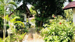 A pathway leading to a row of traditional-style houses surrounded by lush greenery and tropical plants. - Haad Khuad Resort (Ko Pha-ngan)