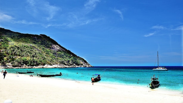 A beach with boats, clear water, and a hilly background. - Haad Khuad Resort (Ko Pha-ngan)