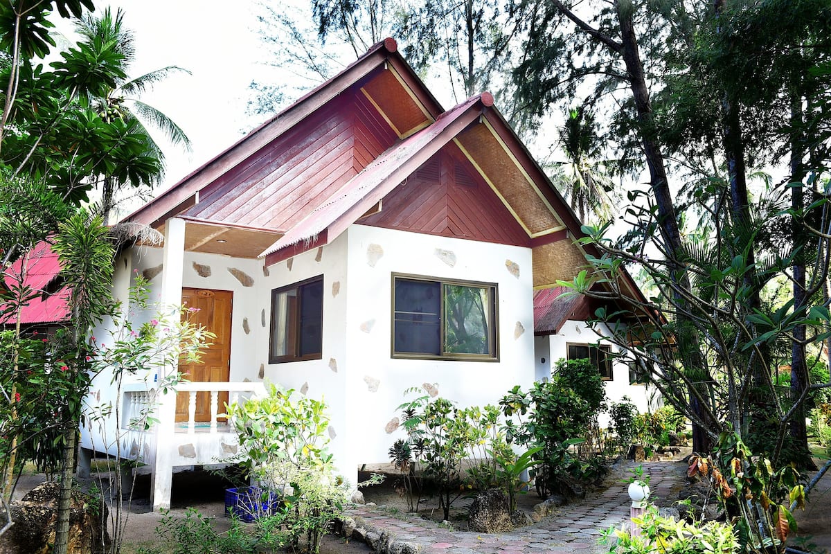 A small house with a red roof, white walls, and a porch.