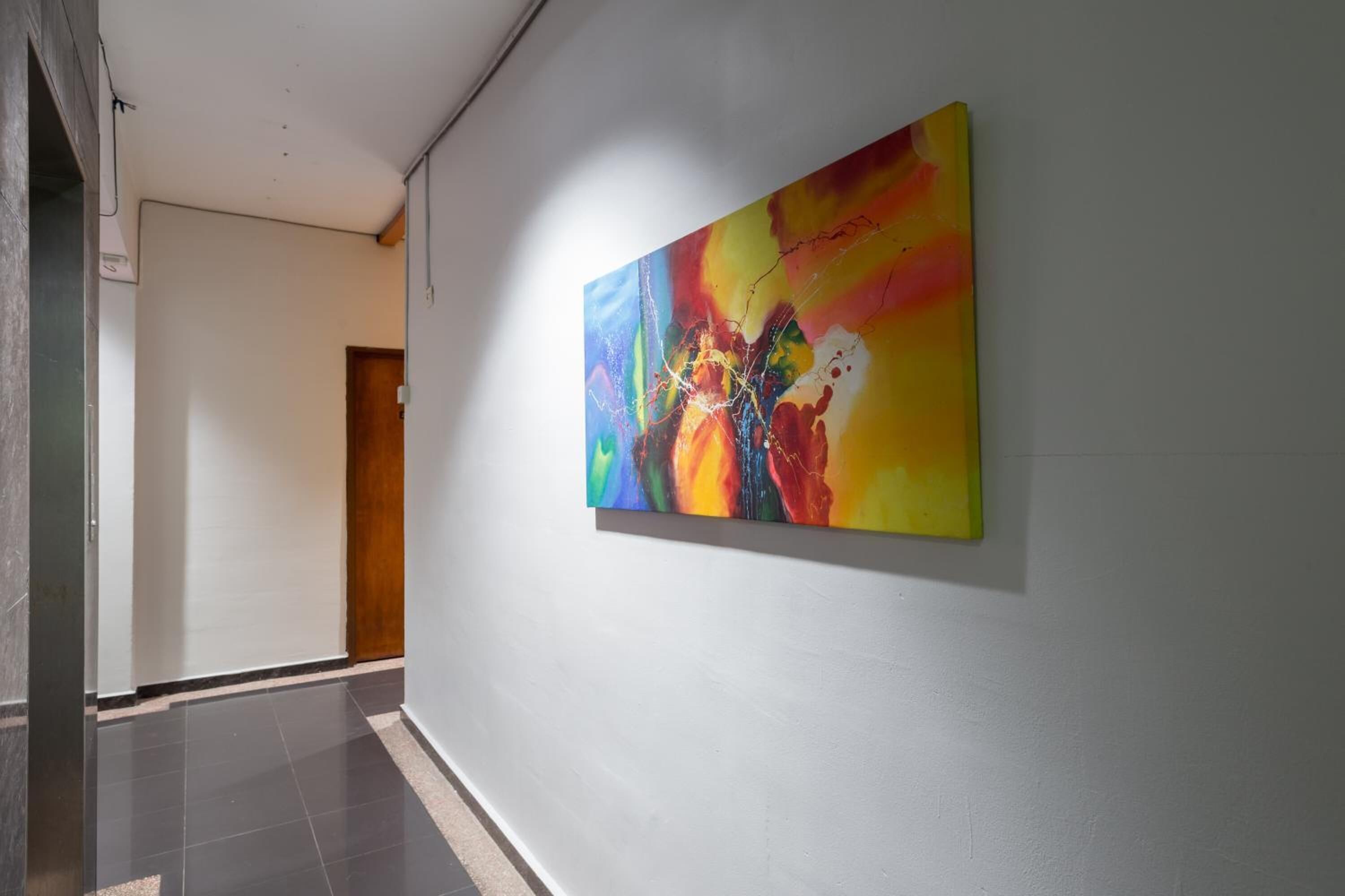 A hallway with a colorful abstract painting on the wall and a door at the end.