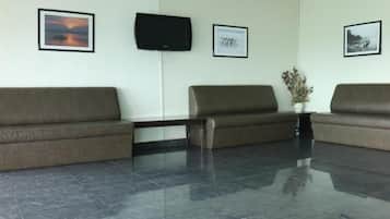A reception area with three brown sofas, a flat-screen TV mounted on the wall, and framed pictures on the walls.