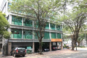 A modern building with a sign for Subang Valley Hotel. There are parked cars and trees in front.