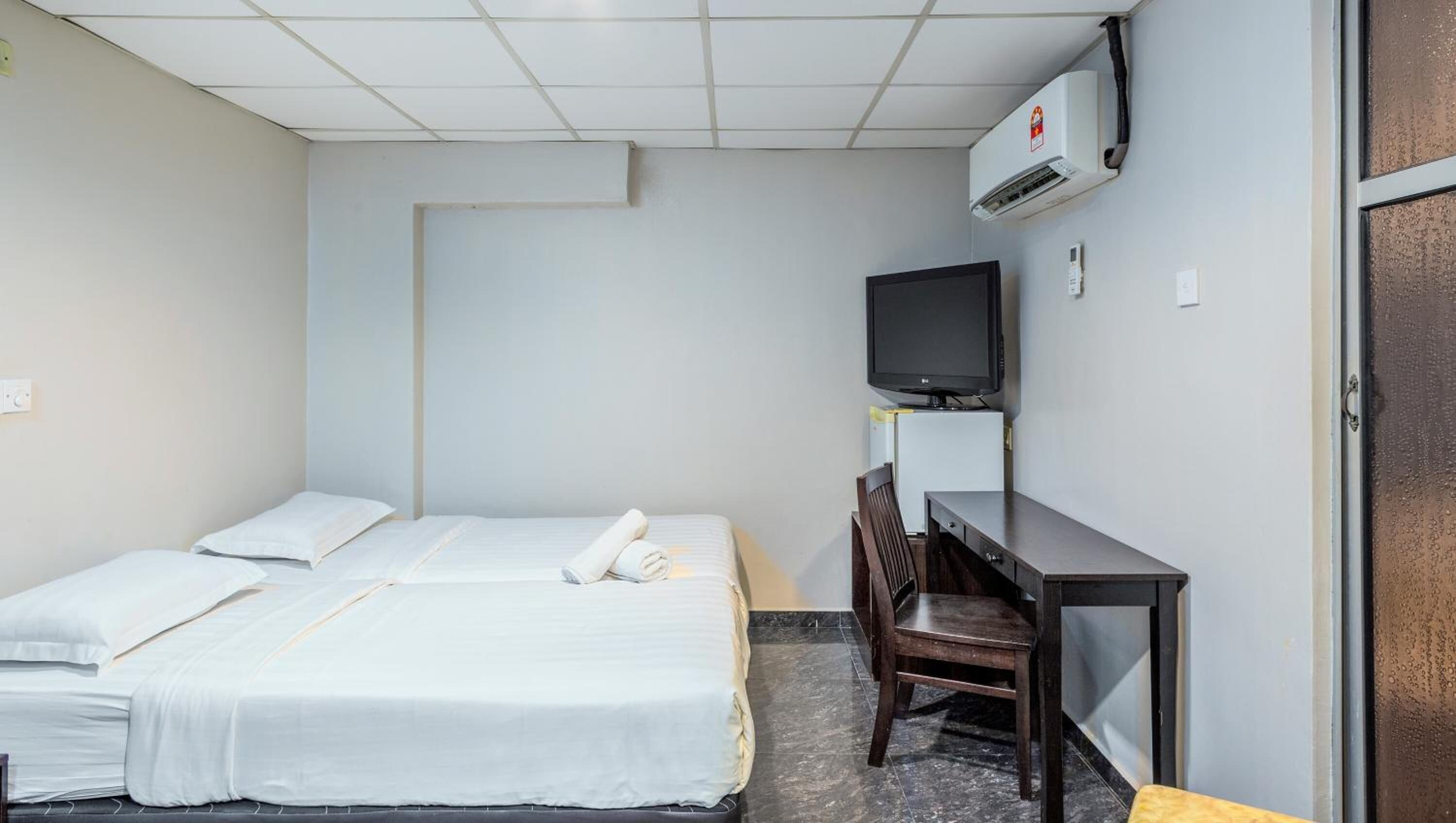 Una habitación de hotel con dos camas, un escritorio, un televisor y un equipo de aire acondicionado.