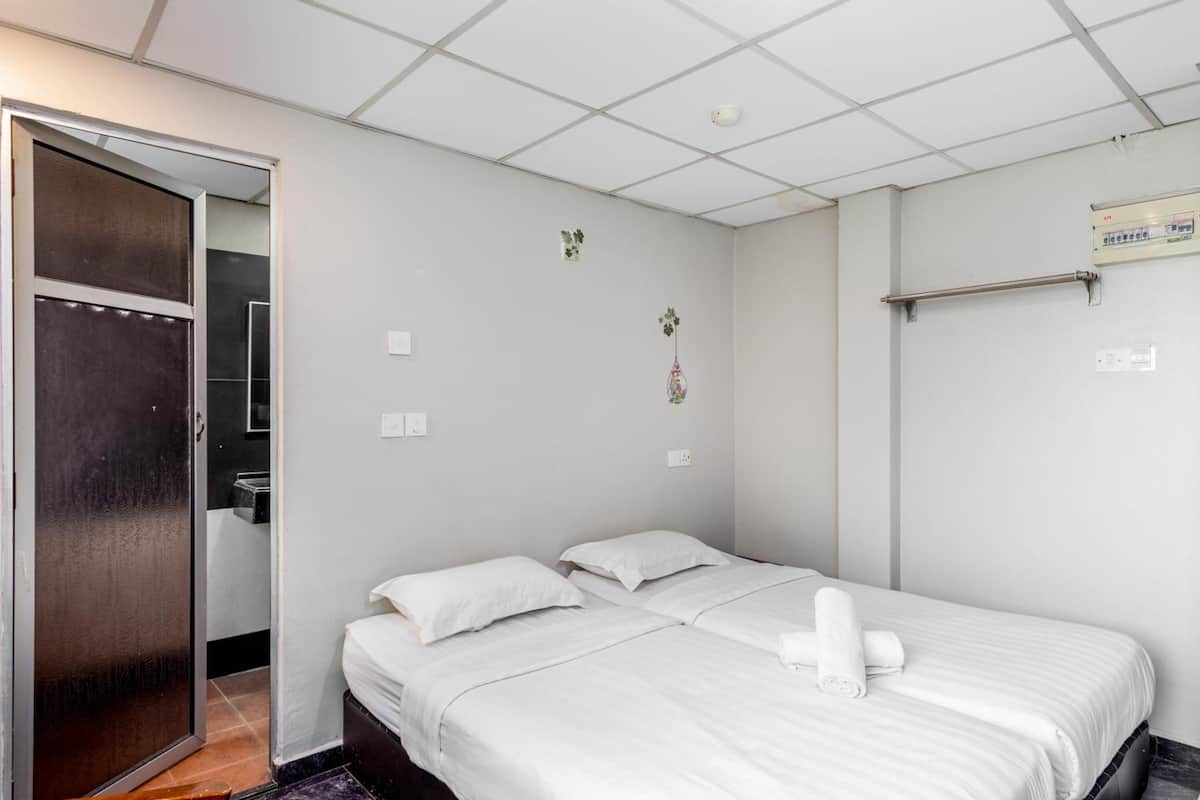A clean, modern hotel room with a bed, a small desk, and a wardrobe.