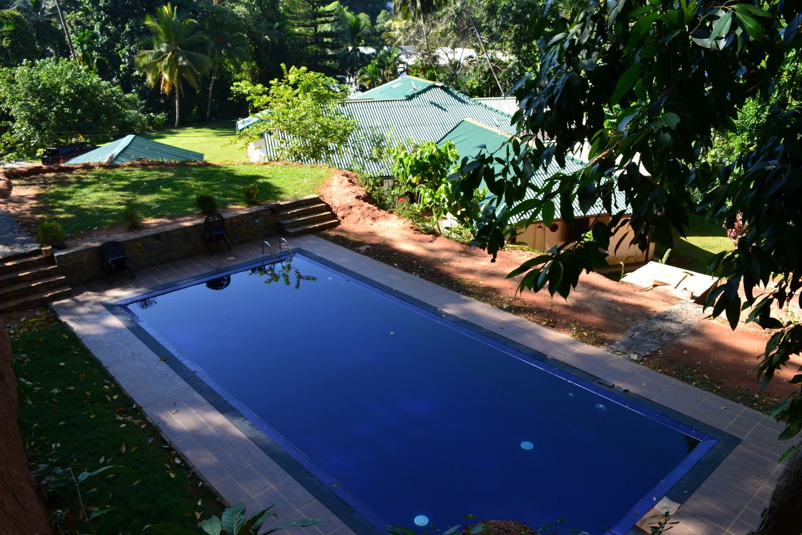 A rectangular swimming pool with a tiled edge, surrounded by a stone border.
