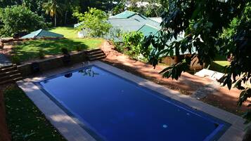 A rectangular swimming pool with a tiled edge, surrounded by a stone border.