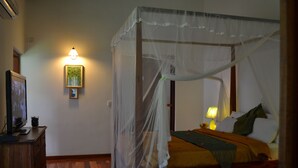 Un dormitorio con cama con dosel, una mesita de noche con lámpara y un cuadro en la pared.