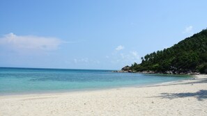 En privat strand, hvidt sand, liggestole, parasoller