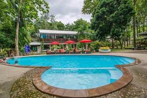 Una piscina al aire libre, sombrillas, sillones reclinables de piscina
