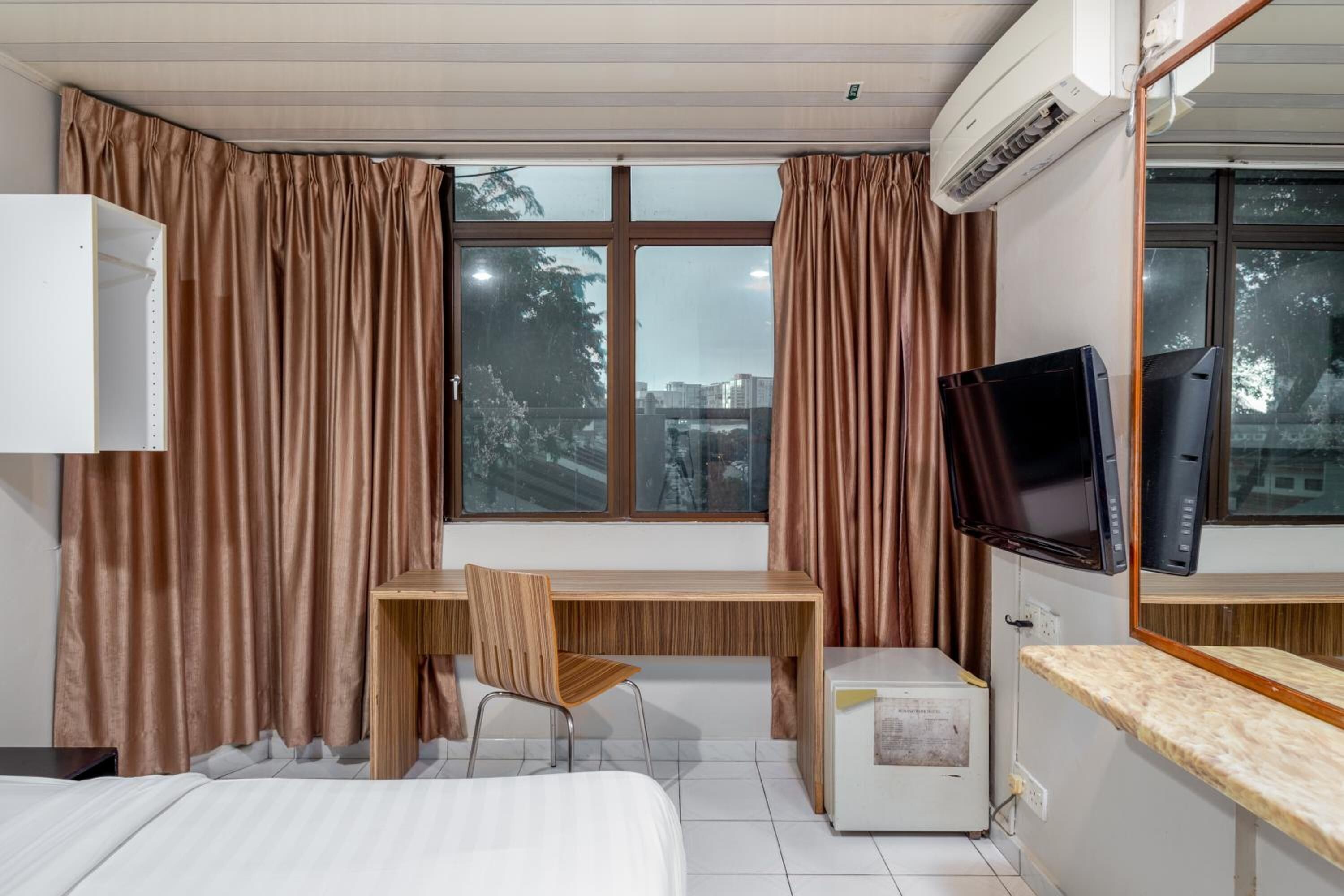 Une chambre d’hôtel équipée d’un lit, d’un bureau avec une chaise, d’une télévision et d’un appareil de climatisation.
