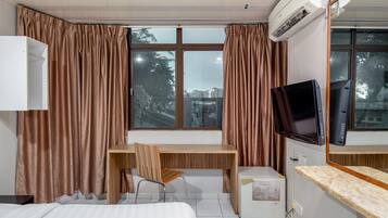 Une chambre d’hôtel équipée d’un lit, d’un bureau avec une chaise, d’une télévision et d’un appareil de climatisation.