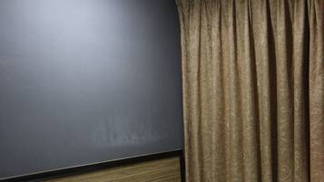 A hotel room with a bed, white linens, a headboard, and a window with curtains.