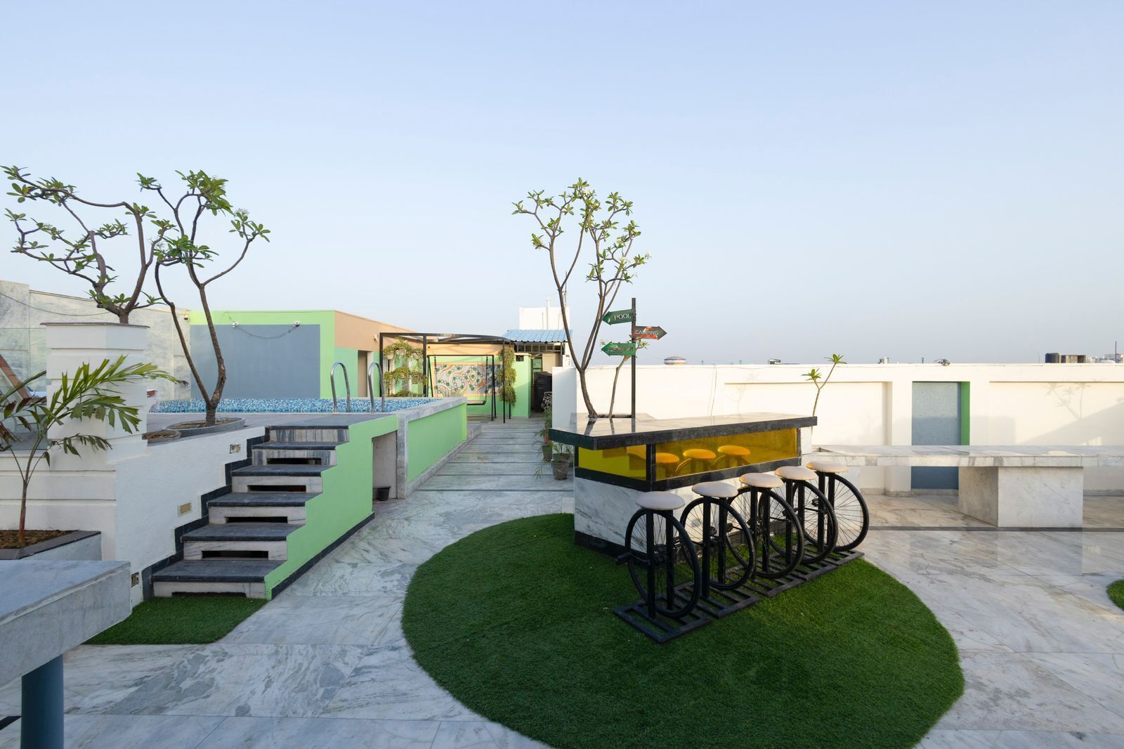 Una terraza en la azotea con zona de bar, asientos y una escalera que sube a un nivel superior.