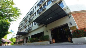 A multi-story hotel with a covered entrance, outdoor plants, and a traditional building in the background. - Telang Usan Hotel (Kuching)