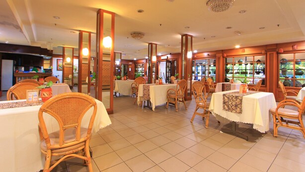 A restaurant with multiple tables and chairs, wooden pillars, and a tiled floor. - Telang Usan Hotel (Kuching)