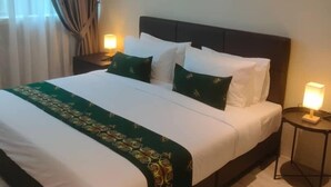 A hotel room with a large bed, a bedside table with a lamp, an air conditioning unit, and a framed picture on the wall. - Telang Usan Hotel (Kuching)