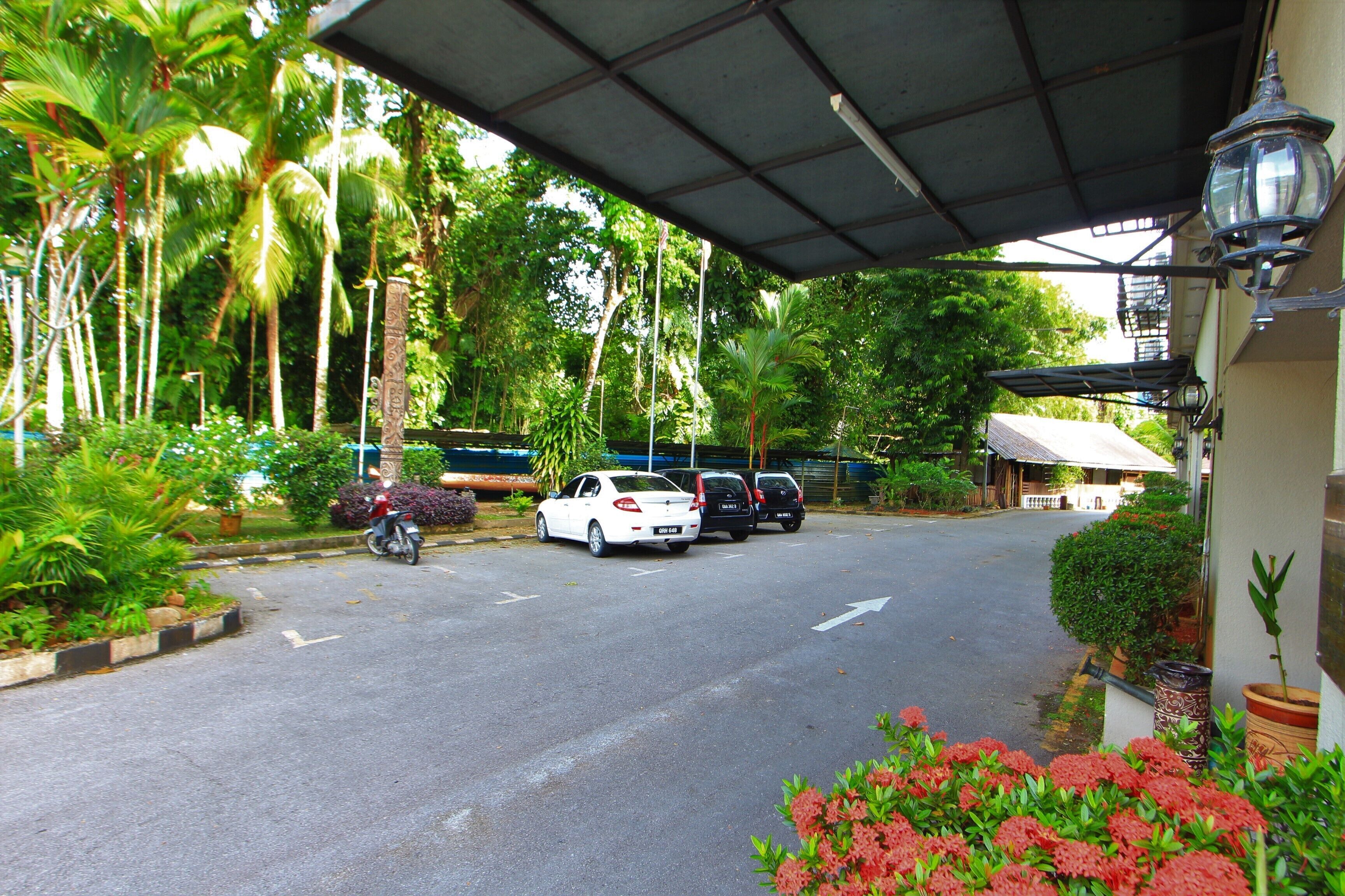 A parking area with a covered walkway, surrounded by lush greenery and palm trees.
