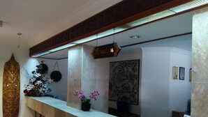 A reception area with a marble counter, decorative wall panels, and a hanging sign. - Telang Usan Hotel (Kuching)
