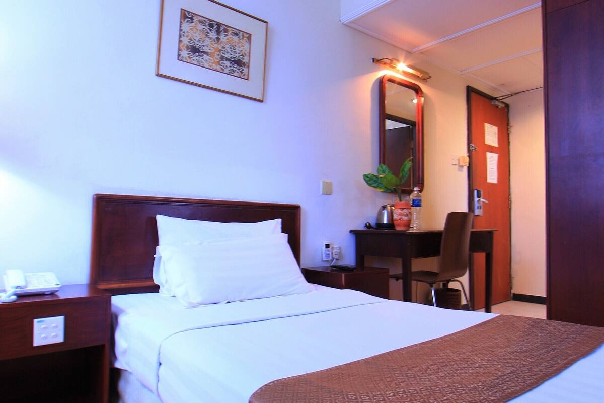 Una habitación de hotel con una cama grande, un escritorio, una silla y un espejo.