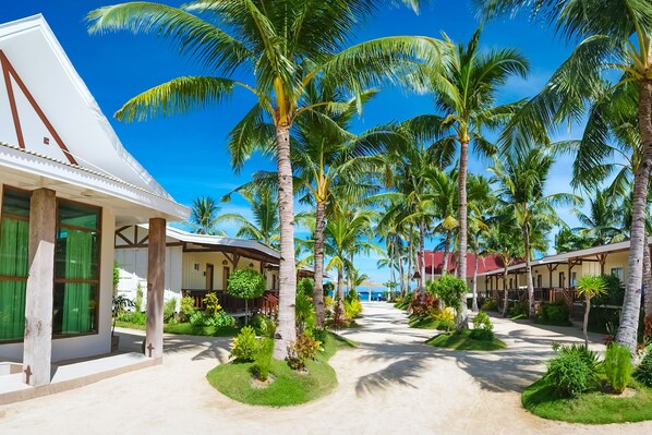 A resort with a covered walkway lined with palm trees and a building with large windows and a red roof.