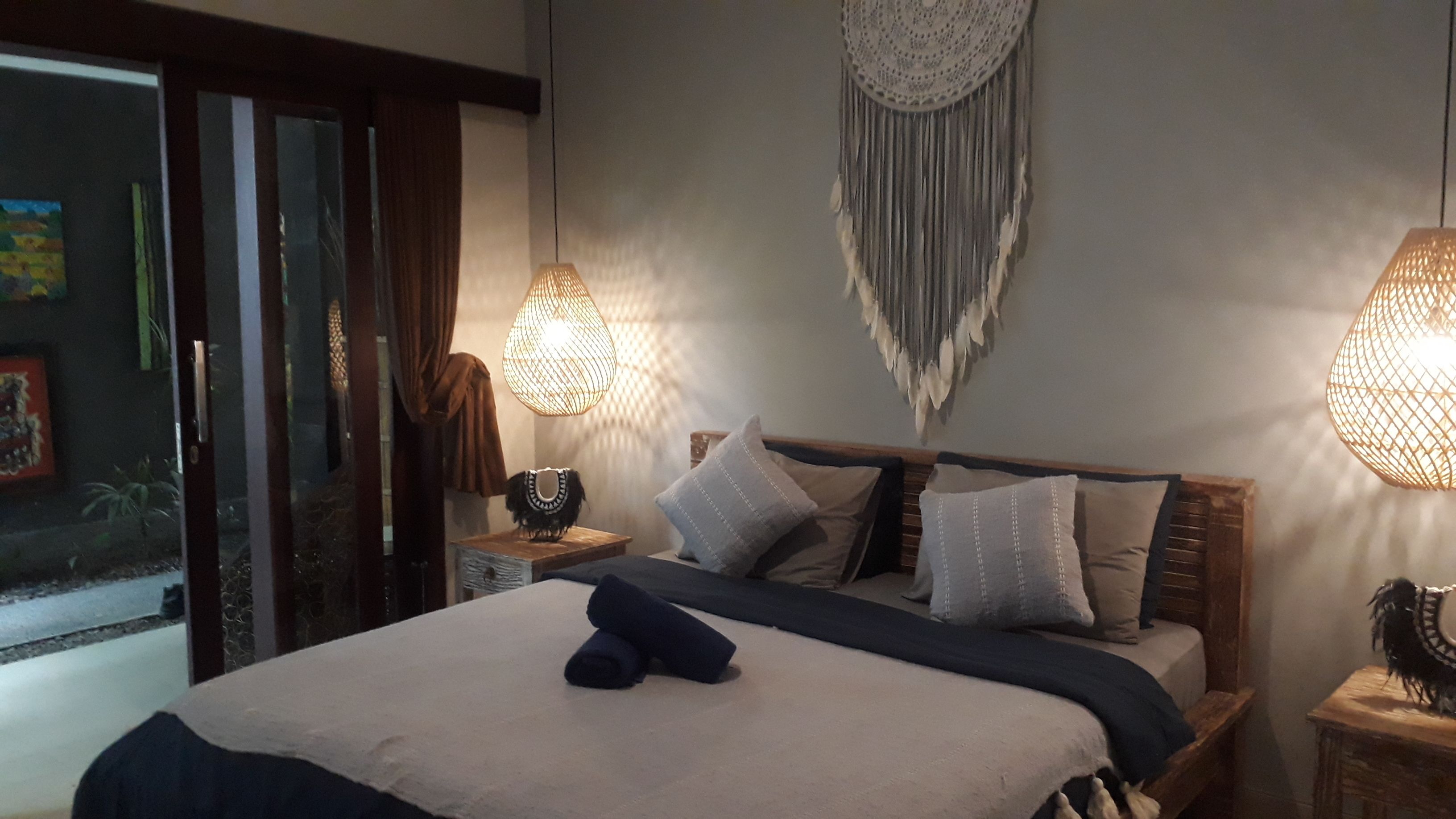 Une chambre à coucher avec un lit, deux tables de chevet, une décoration murale et une porte.