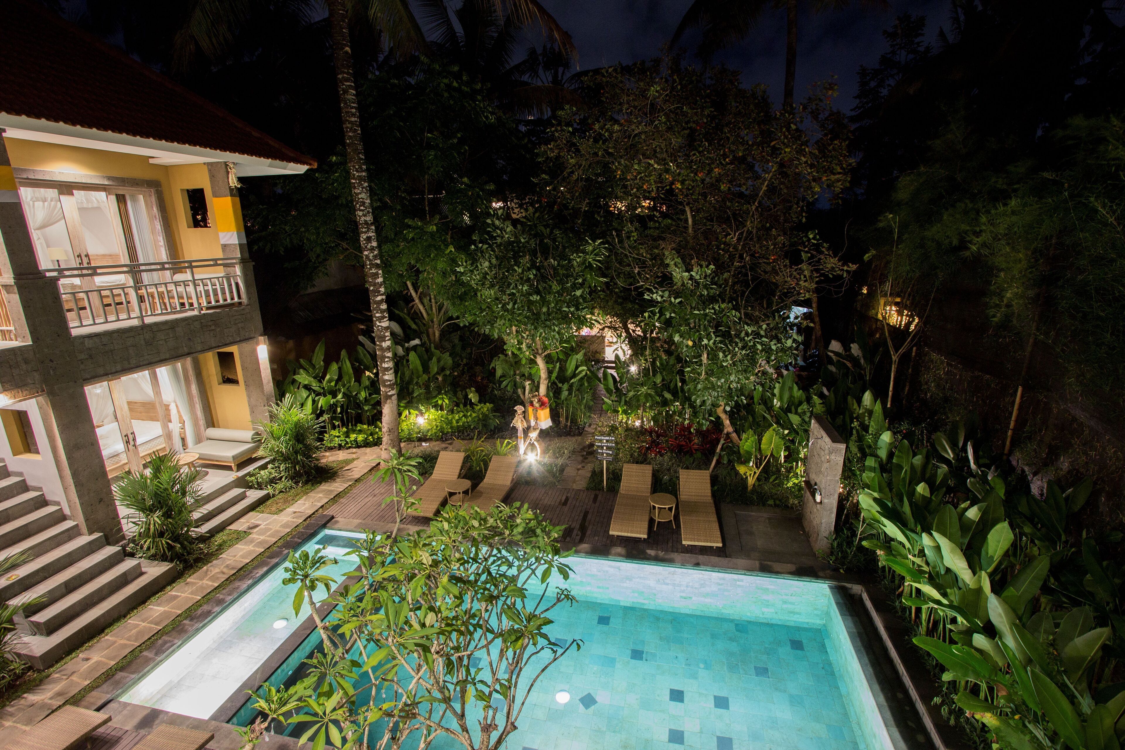 A pool area with lounge chairs, a small pool, and a staircase leading to a balcony.