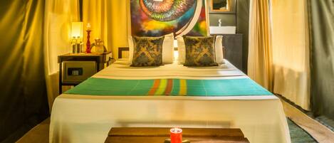 A room with a bed, a nightstand, a lamp, and a tapestry.