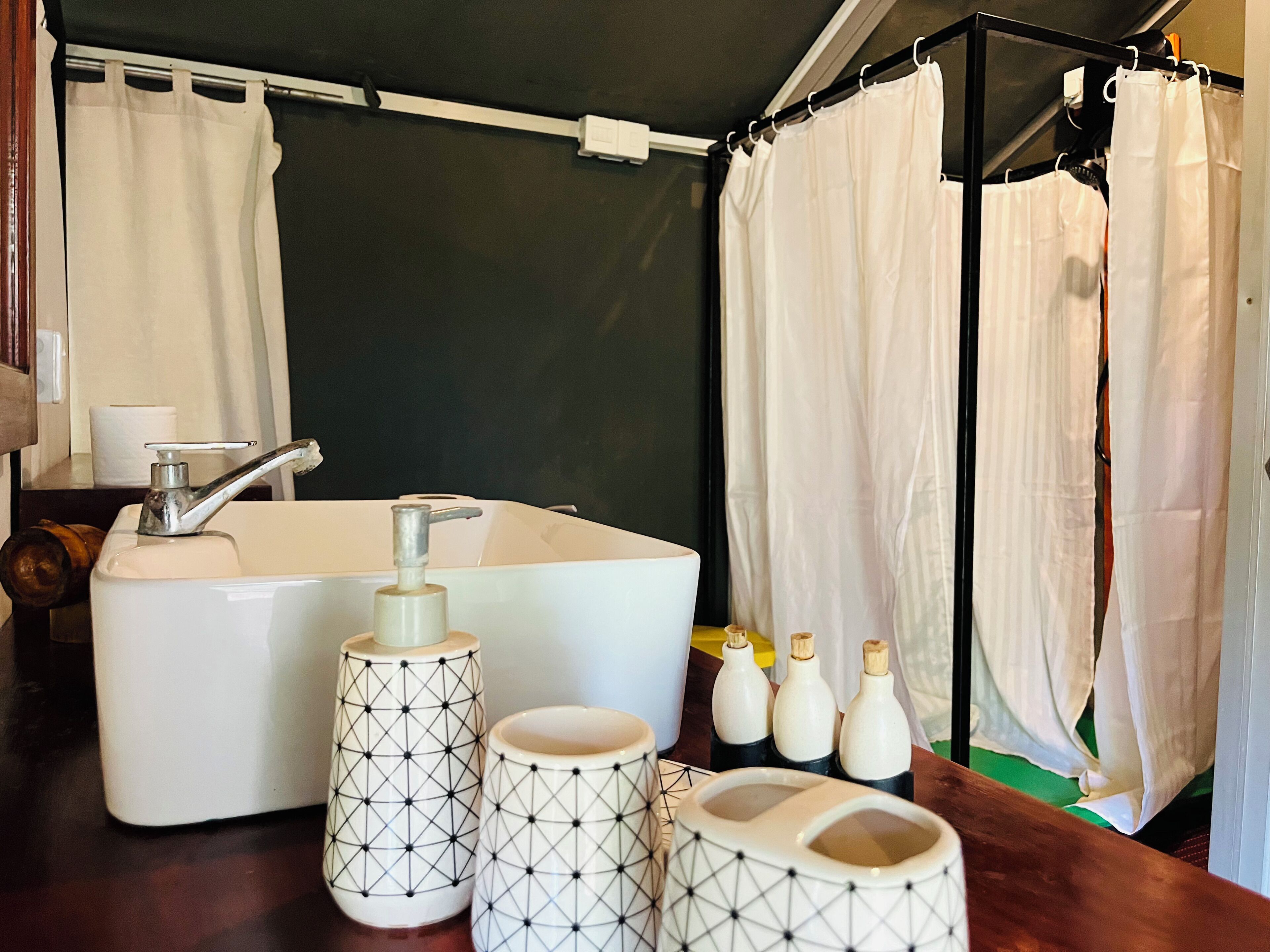 A bathroom with a large bathtub, a sink, and three toiletry bottles on the counter.