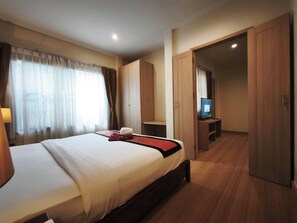 A hotel room with a bed, a television, a wardrobe, and a desk. - Happy Cottages Phuket (Chalong)