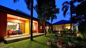A modern hotel with a well-maintained garden, outdoor seating, and a variety of decorative elements. - Happy Cottages Phuket (Chalong)