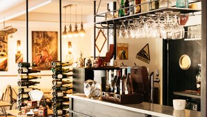 Eine Bar mit einer schwarzen Theke, Weinflaschen, Gläsern und einer Kaffeemaschine.