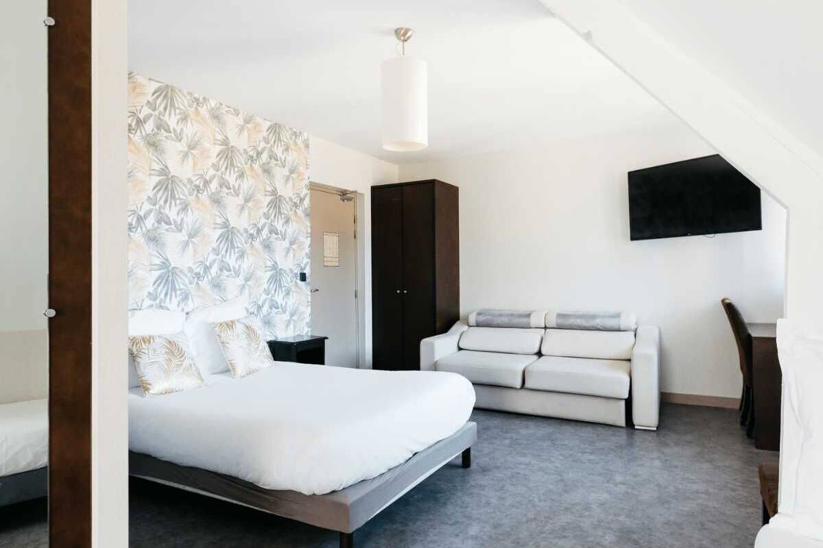 Une chambre à coucher comprenant un lit, un canapé, une armoire et un téléviseur fixé au mur.