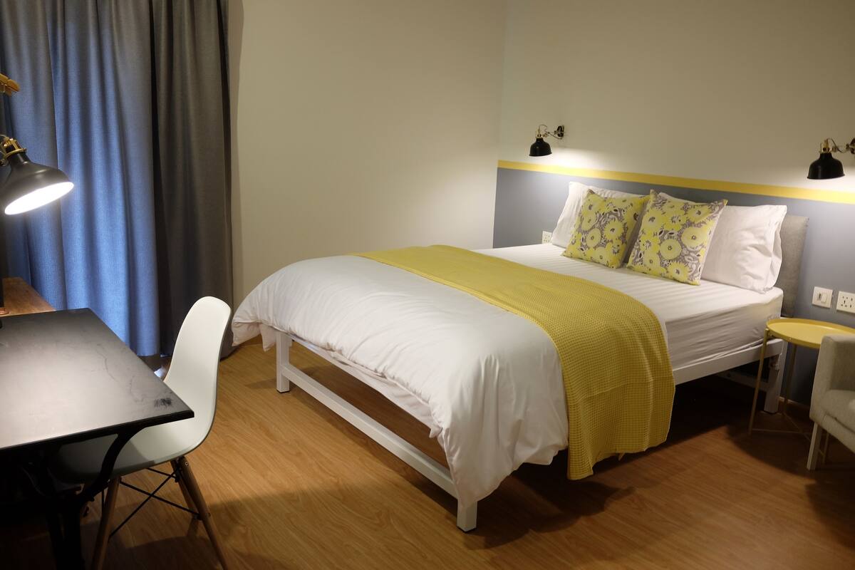 A neatly arranged hotel room with a bed, bedside tables, a desk, and a chair.
