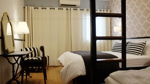 A hotel room with a four-poster bed, a desk with a chair, a mirror, and a window with curtains. - Vimarn Hostel (Bangkok)