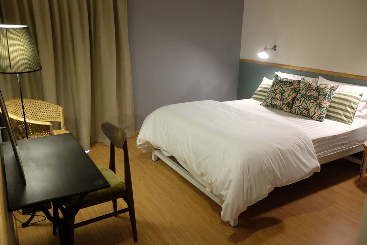A neatly arranged hotel room with a bed, a table, and a chair.