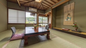 Ett traditionellt japanskt rum med tatamimattor på golvet, ett träbord och shojiskärmar.