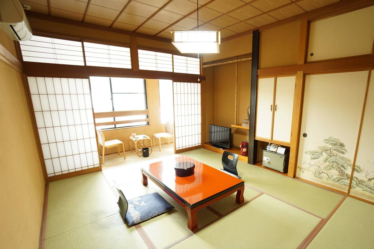 A traditional Japanese room with tatami flooring, a low table, and sliding doors.