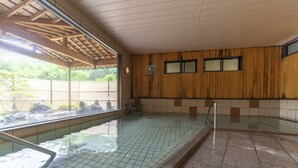 En swimmingpool med kakelbeklädd botten, träväggar och ett takförsett område.