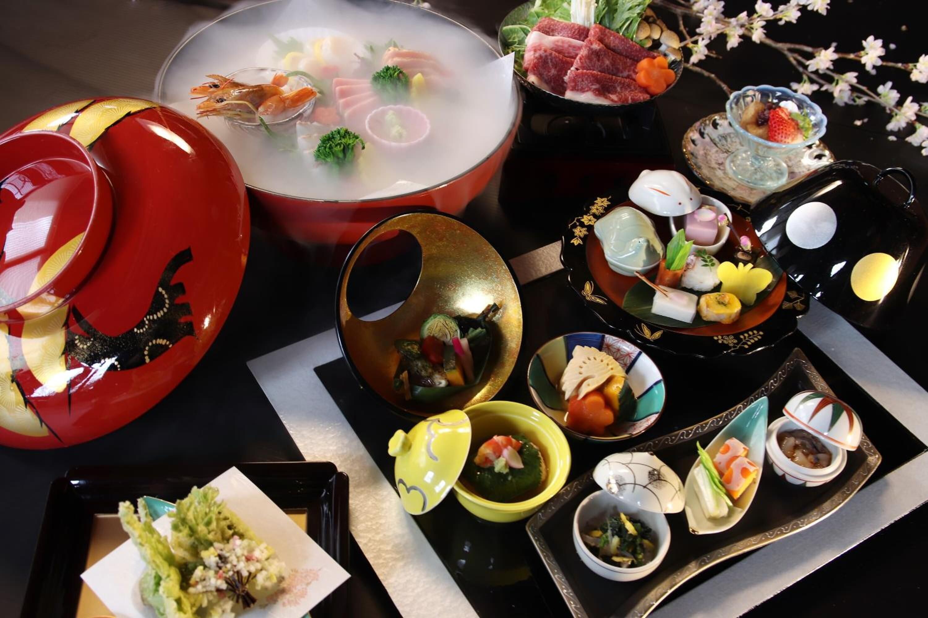 Verschiedene japanische Gerichte, darunter Sushi, Sashimi und ein Hot Pot, sind auf einem Tisch angerichtet.