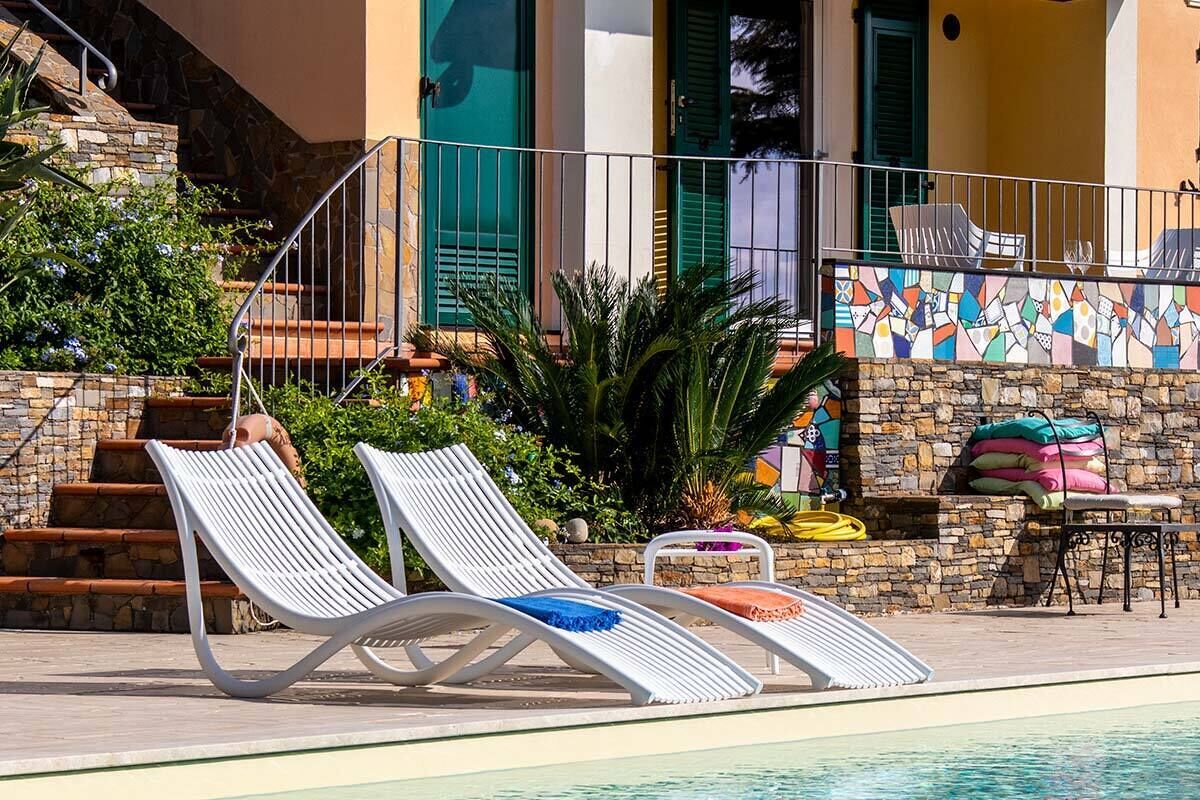 A poolside area with lounge chairs, a stone staircase, and a colorful mosaic wall.