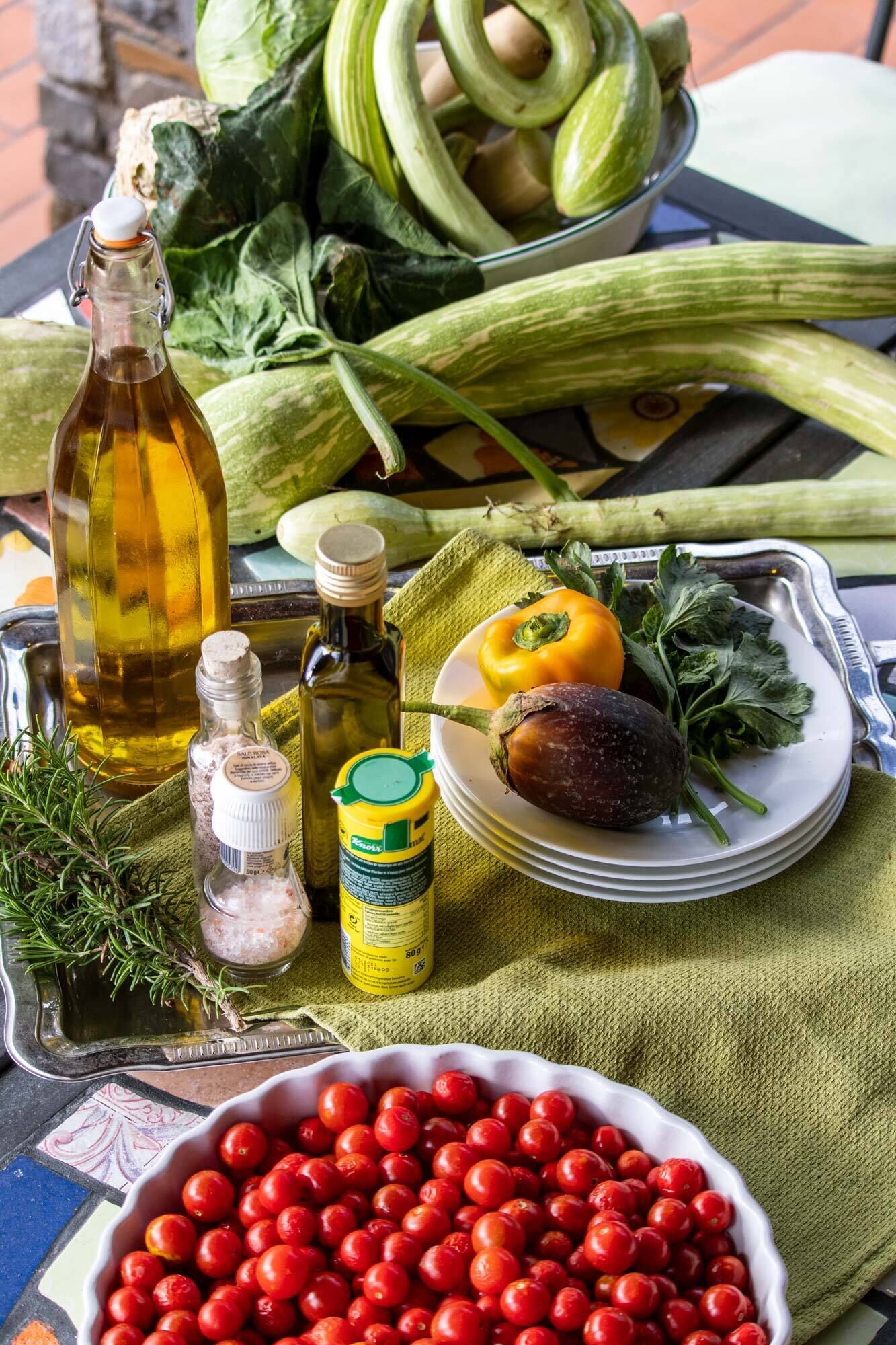 Une table sur laquelle on trouve divers aliments, notamment des légumes, une bouteille d’huile et des condiments.