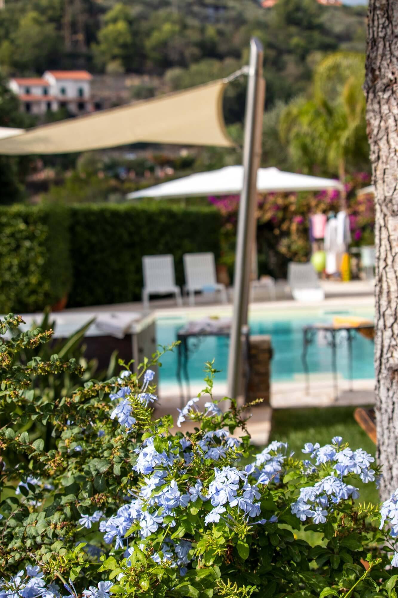A pool area with lounge chairs and a shaded umbrella.